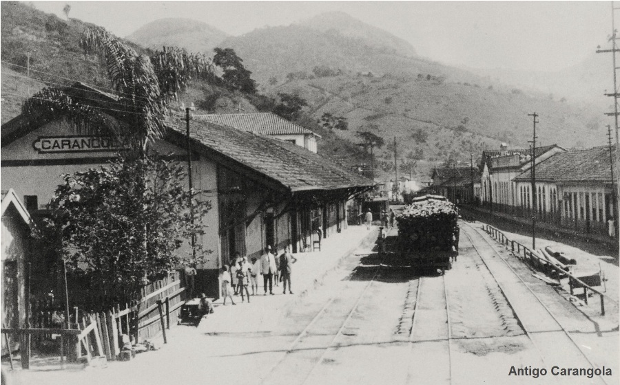 Fotografia histórica da estação de Carangola com uma composição ferroviária e pessoas na plataforma